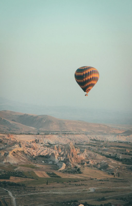a hot air balloon flying over a valley, by Daren Bader, pexels contest winner, renaissance, low quality photo, islamic, drone footage, vacation photo
