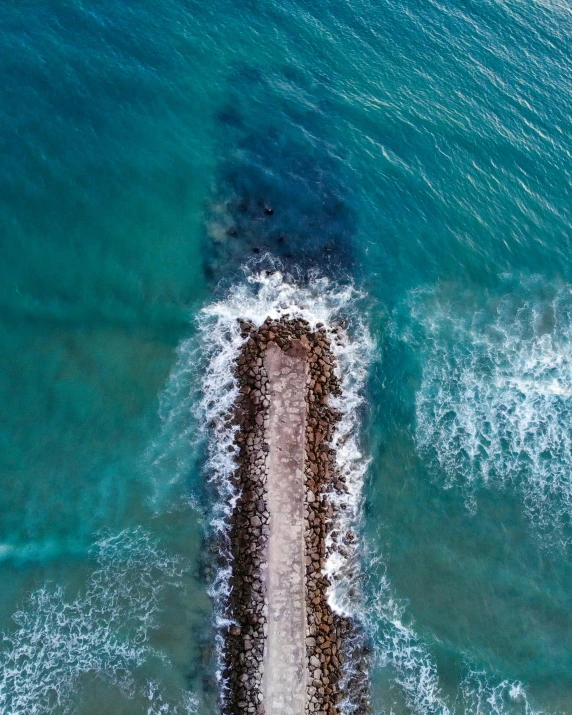 an aerial view of a pier in the middle of the ocean, pexels contest winner, land art, wall of water either side, sea foam, posing for camera, splash image