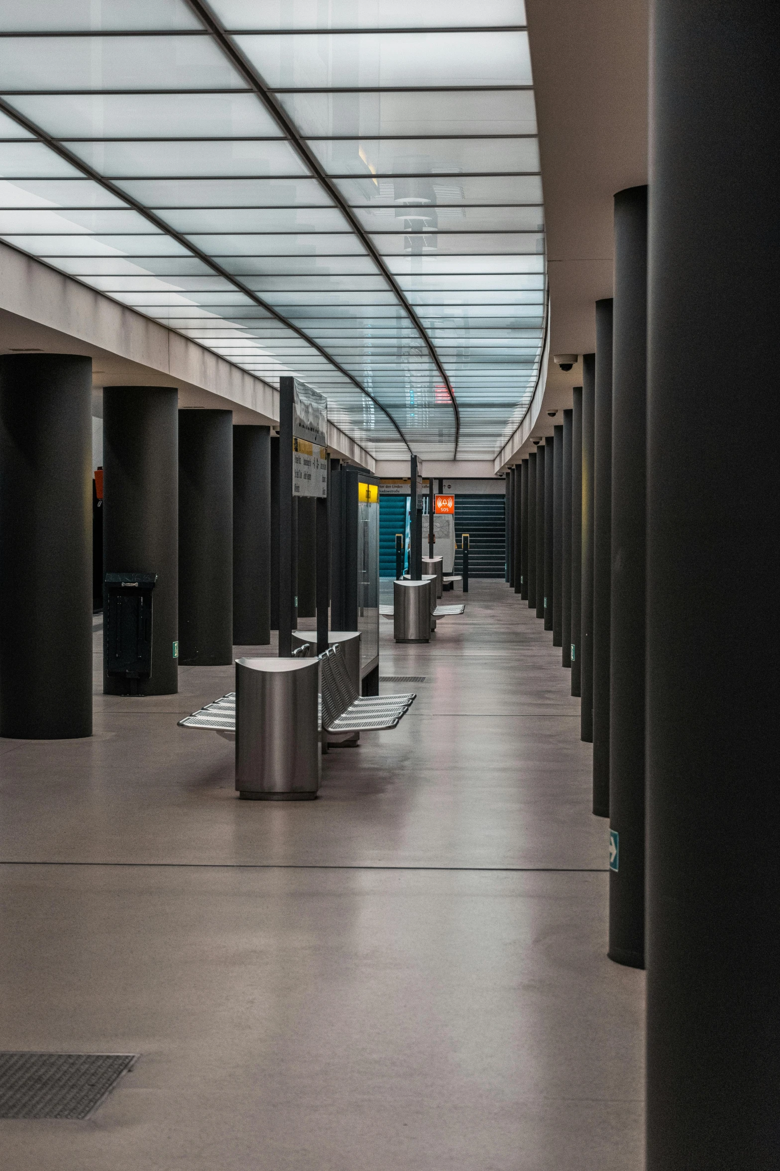 a view of the inside of a train station, inspired by David Chipperfield, unsplash, modernism, adorned pillars, painted metal and glass, long dark hallway, museum exhibit