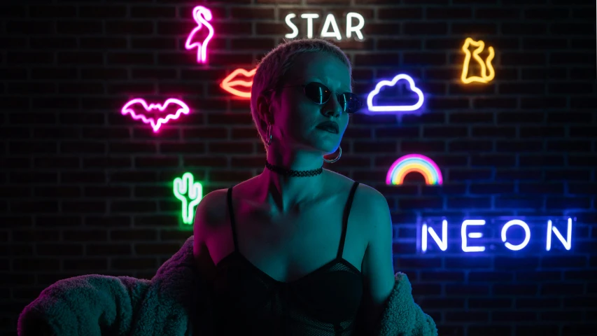 a woman sitting on a couch in front of neon signs, trending on pexels, killstar, non binary model, night sky, neon standup bar