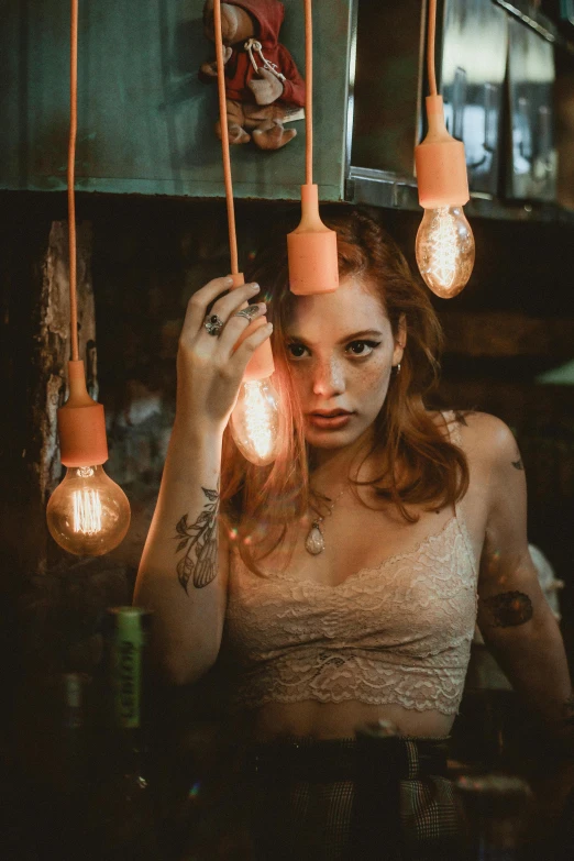 a woman holding a light bulb over her head, a portrait, inspired by Elsa Bleda, trending on pexels, a redheaded young woman, sexy gaze, party lights, with tattoos