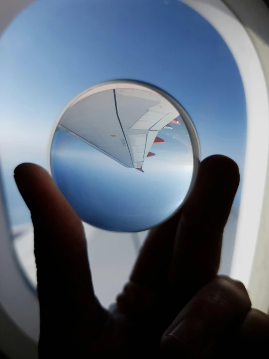 a view of the wing of an airplane through a window, inspired by Leandro Erlich, pexels contest winner, holding a crystal ball, circular glasses, 8k selfie photograph, flying over a red sea