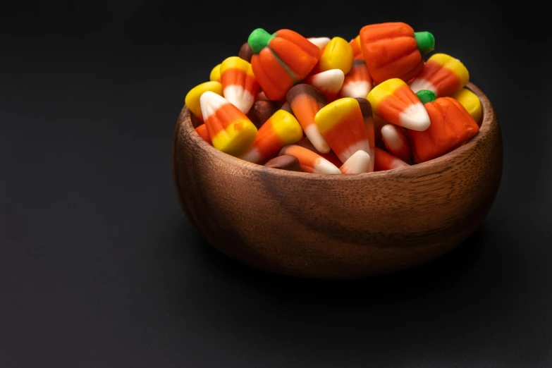 a wooden bowl filled with candy corn, pexels, visual art, square, dark. no text, profile image, fan favorite