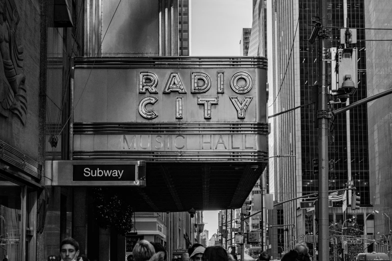a group of people walking down a street next to tall buildings, an album cover, by Dan Frazier, unsplash contest winner, madison square garden, black and white image, radios, neon city domes
