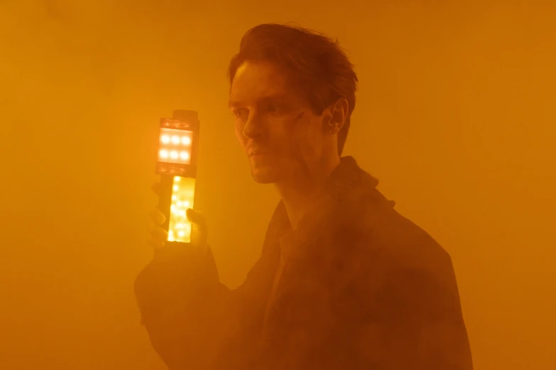 a man holding a light up to his face, unsplash contest winner, bauhaus, yellow mist, movie still 8 k, altered carbon series, ignant