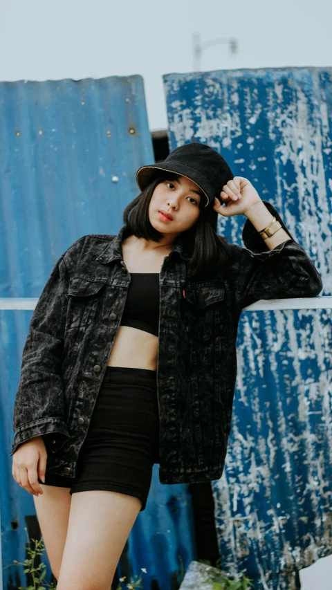 a woman standing in front of a blue wall, an album cover, inspired by Elsa Bleda, pexels contest winner, black hat, cropped shirt with jacket, asian girl, 15081959 21121991 01012000 4k