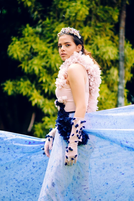 a woman that is standing in the grass, an album cover, by reyna rochin, unsplash, renaissance, feather boa, isabela moner, blue colored traditional wear, at a fashion shoot