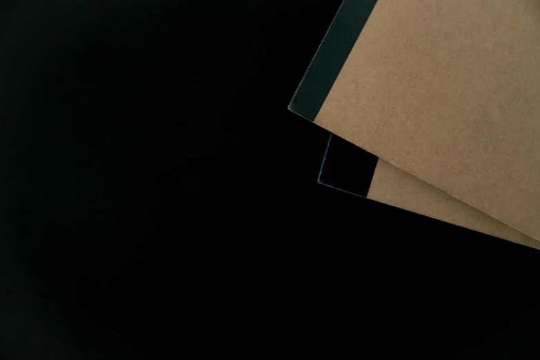 a pile of brown paper sitting on top of a black table, an album cover, inspired by Colin McCahon, unsplash, postminimalism, black blue green, ignant, profile close-up view, panel of black