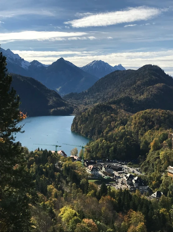 a large body of water sitting on top of a lush green hillside, the alps are in the background, autumn mountains, skiing, thumbnail