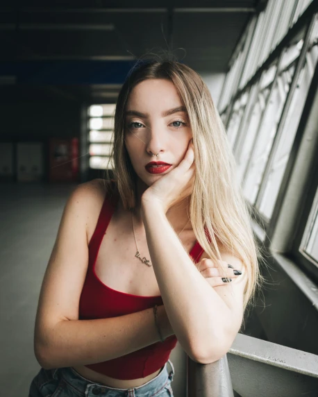 a beautiful young woman standing next to a window, inspired by Elsa Bleda, trending on pexels, red tank-top, nonbinary model, in a spaceship, lovingly looking at camera