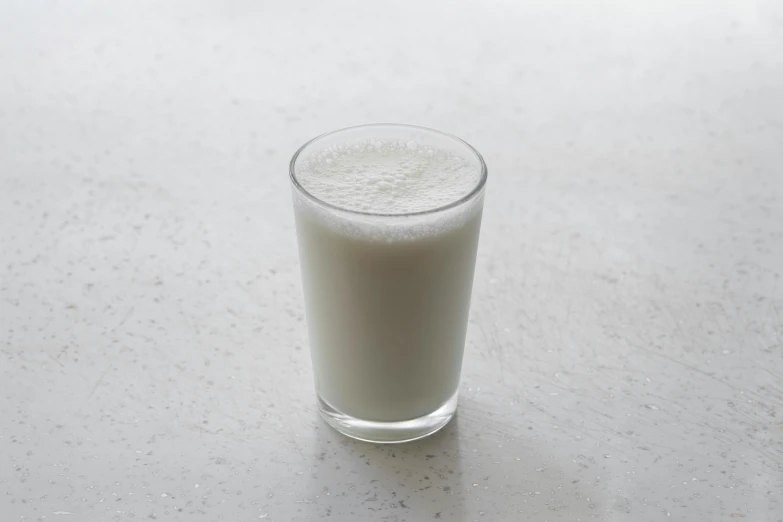 a glass of milk sitting on a table, light grey mist, detailed product image, 3/4 front view, soymilk