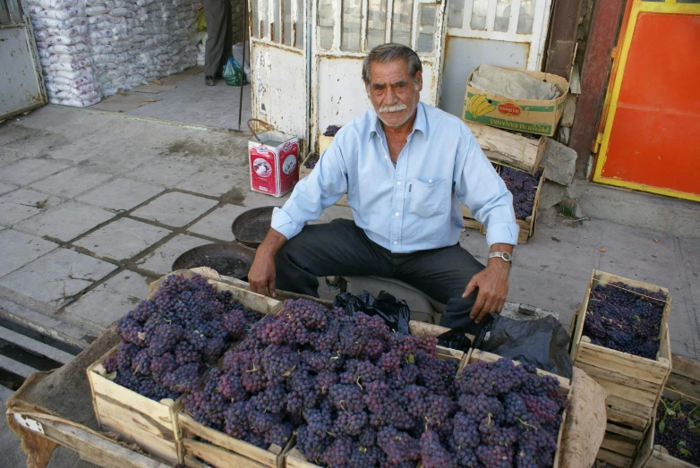 a man sitting in front of a crate of grapes, by Edward Ben Avram, pexels, hurufiyya, turkey, amethyst, neighborhood, 2 0 1 0 photo