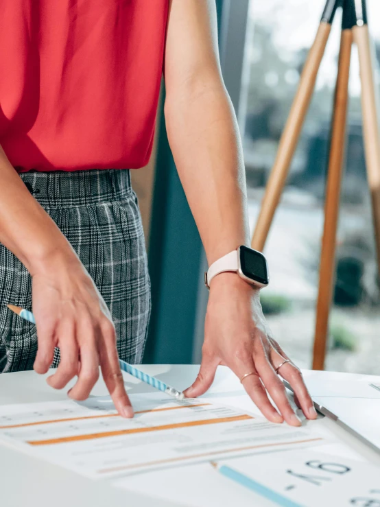 a woman cutting a piece of paper with a pair of scissors, trending on unsplash, wearing business casual dress, watch photo, colorful architectural drawing, standing on a desk