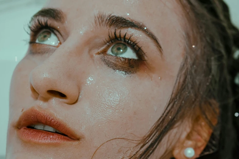 a close up of a woman with water on her face, inspired by Elsa Bleda, trending on pexels, hyperrealism, glitter gif, girl with a pearl earringl, young woman looking up, hyperrealistic photo