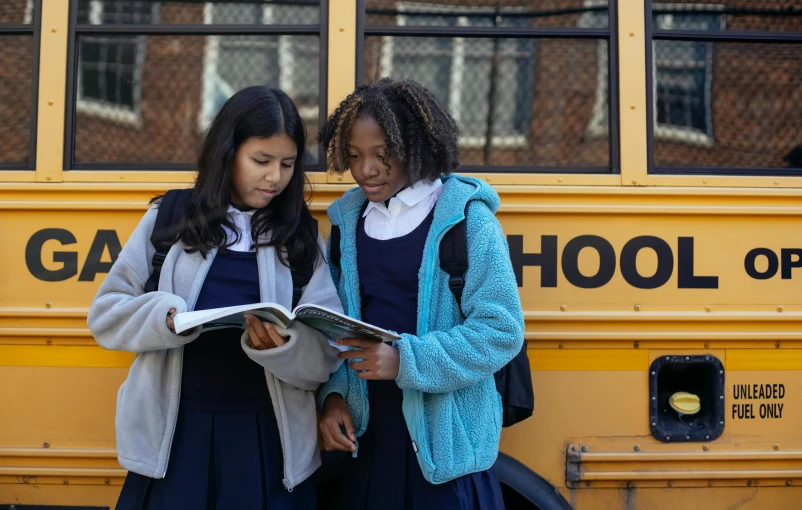 two girls standing in front of a school bus, by Carey Morris, pexels, ashcan school, holding books, live-action adaptation, mid morning lighting, sirius a and sirius b