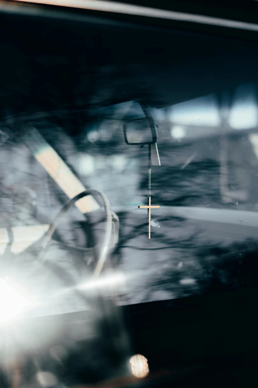 a close up of the dashboard of a car, an album cover, inspired by Elsa Bleda, conceptual art, shadow of catholic church cross, blurred lost edges, reflections and refractions, crosses