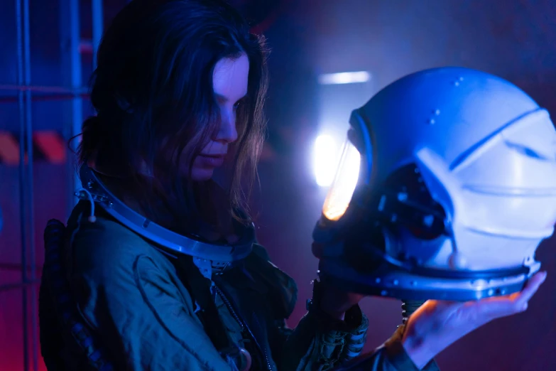 a close up of a person holding a helmet, a portrait, by David Donaldson, pexels contest winner, beautiful woman in spacesuit, clara oswald, extremely moody blue lighting, spaceship being repaired