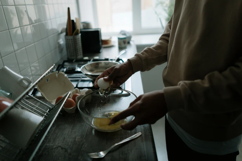 a person in a kitchen preparing food on a counter, pexels contest winner, an egg, straining, standing, mid riff