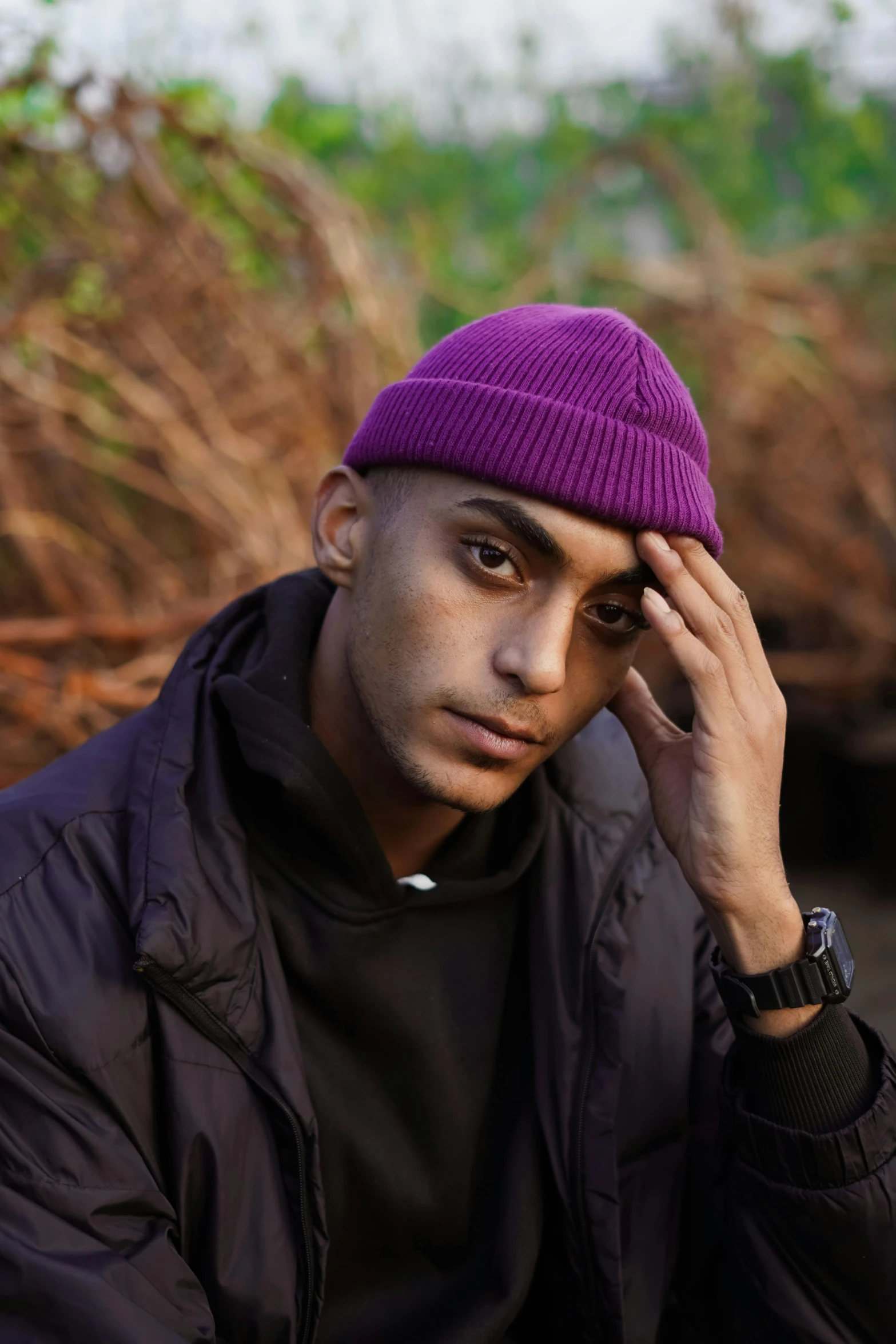 a man in a purple hat sitting on the ground, trending on pexels, beanie, non binary model, hasan piker, headshot profile picture