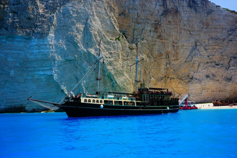 a boat that is sitting in the water, by Simon Marmion, pexels contest winner, renaissance, greek nose, geology, pirate themed, black and cyan color scheme