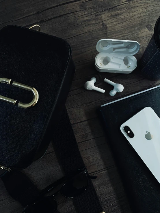 a black bag sitting on top of a wooden table, a still life, trending on pexels, bling airpods, white biomechanicaldetails, low quality photo, headset