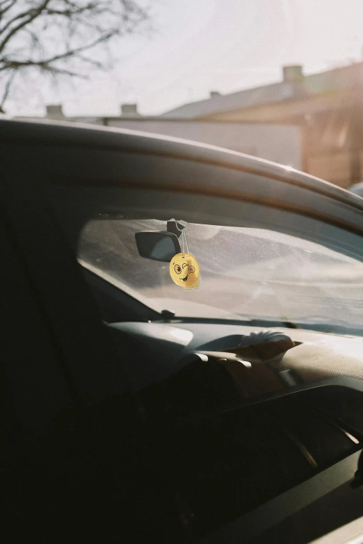 a close up of a car window with a sticker on it, by Attila Meszlenyi, unsplash, wearing a lemon, pareidolia, cinematic shot, low quality photo