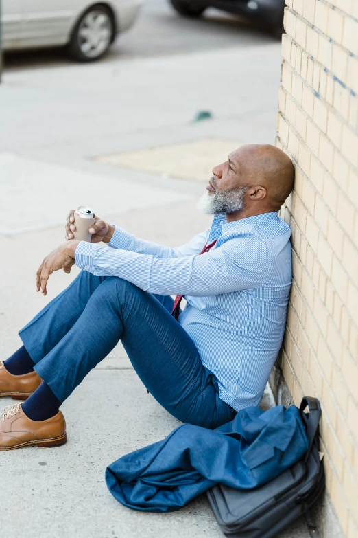 a man sitting on the sidewalk with a cup of coffee, inspired by William H. Mosby, looking exhausted, bald head and white beard, leaning against the wall, looking at his phone