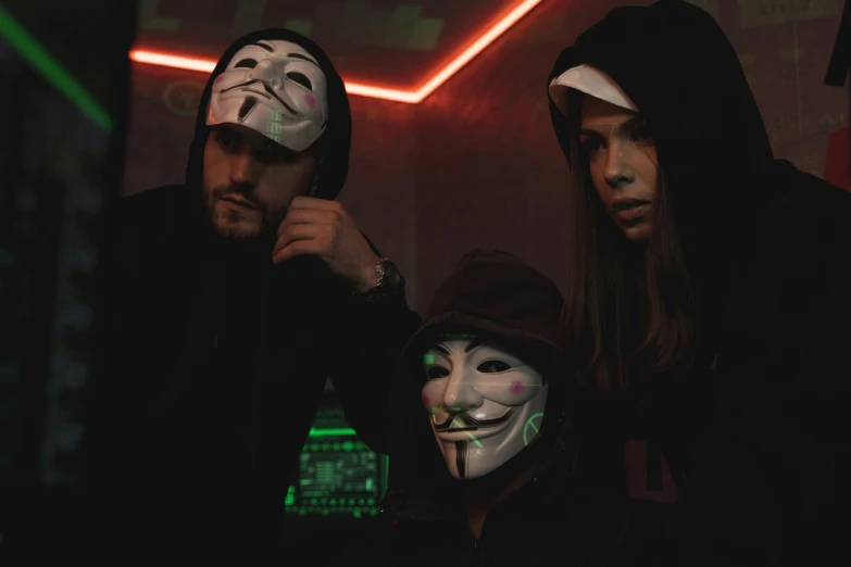 a group of people wearing masks in a dark room, a hologram, pexels contest winner, antipodeans, wearing jeans and a black hoodie, 🕹️ 😎 🔫 🤖 🚬, anarchy, anonymous