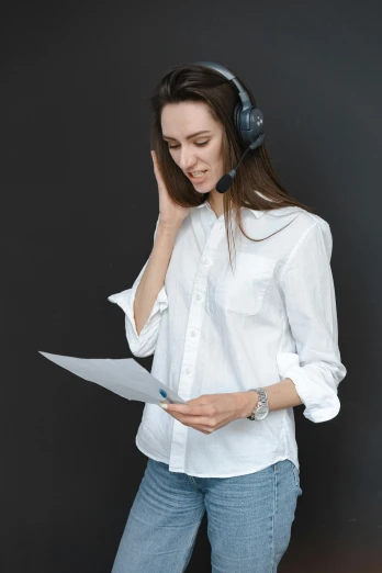 a woman wearing headphones and holding a piece of paper, on a gray background, wearing a light shirt, multiple stories, uploaded