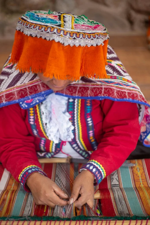 a woman that is sitting down on a rug, process art, quechua, square, traditional tai costume, brown