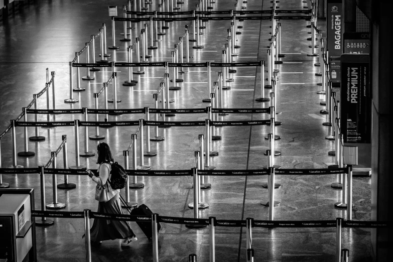 a black and white photo of a woman walking through an airport, by Matthias Weischer, pexels contest winner, happening, barriers, lamps on ground, covid, concert