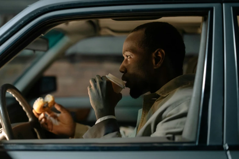 a man sitting in a car eating a hot dog, inspired by Gordon Parks, pexels contest winner, portrait of morning coffee, dark skinned, worksafe. cinematic, [ theatrical ]