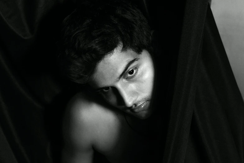 a black and white photo of a shirtless man, a black and white photo, by irakli nadar, renaissance, with haunted eyes and dark hair, 14 yo berber boy, black cloak hidden in shadows, riccardo scamarcio