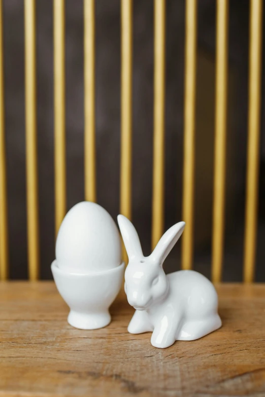 a white rabbit figurine sitting next to an egg, salt shaker, hero shot, white, mini