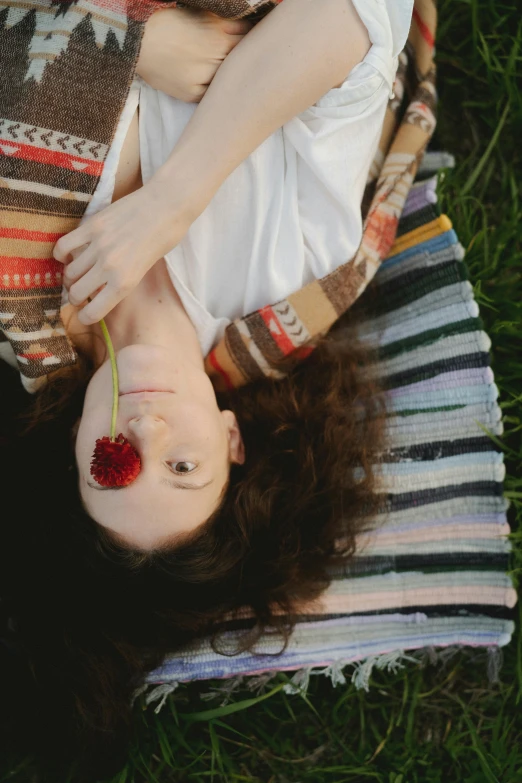 a woman laying on a blanket in the grass, inspired by Elsa Bleda, pexels contest winner, renaissance, girl with a flower face, hanging upside down, eating, close-up portrait film still