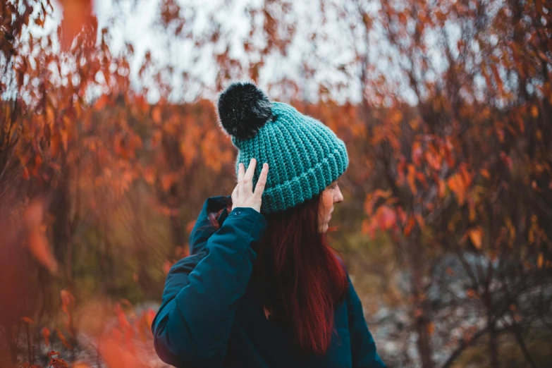 a woman talking on a cell phone in a forest, by Emma Andijewska, trending on pexels, wearing teal beanie, ( redhead, with soft bushes, woman with black hair