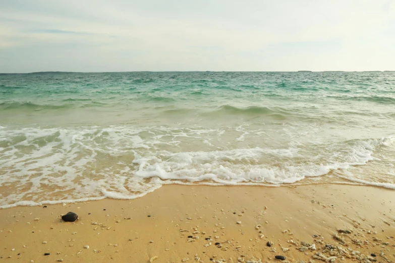 a large body of water sitting on top of a sandy beach, by Robbie Trevino, on the sea, green sea, rough waters, seaview