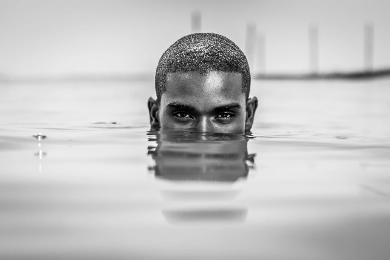 a black and white photo of a man in the water, by Daniel Gelon, brown skinned, portrait 8 k, flooded, pupil