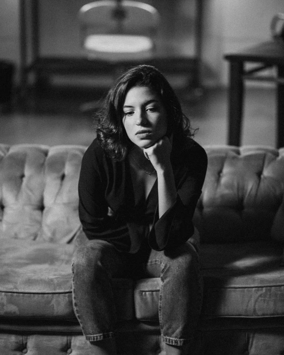 a black and white photo of a woman sitting on a couch, unsplash, renaissance, arab young monica belluci, taken in the mid 2000s, on a dark background, medium poly