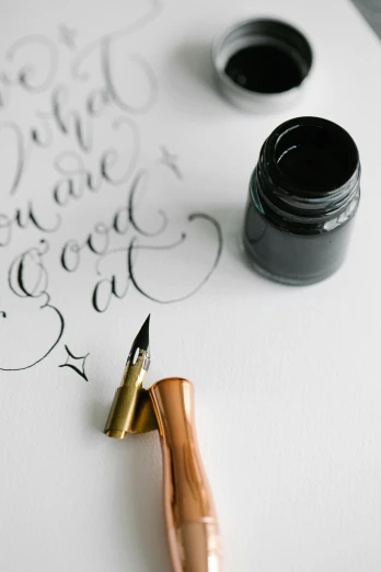 a pen sitting on top of a piece of paper, an ink drawing, calligraphy, charcoal and champagne, all black matte product, bold. intricate