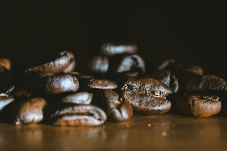 a pile of coffee beans sitting on top of a wooden table, jen atkin, dimly - lit, background image, uploaded