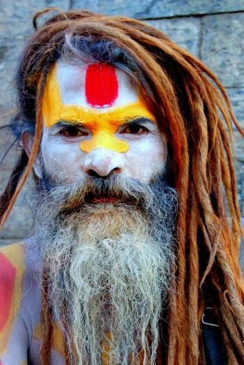 a man with dreads and a painted face, an album cover, inspired by Steve McCurry, pexels contest winner, renaissance, hindu gods, long and orange mustache, holy ceremony, a photo of a disheveled man