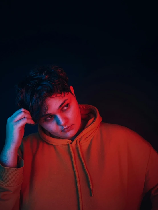 a man in a red hoodie posing for a picture, an album cover, inspired by Ion Andreescu, pexels contest winner, bisexual lighting, joel fletcher, desaturated, andy milonakis