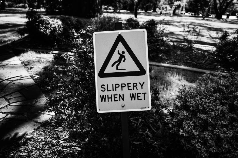 a black and white photo of a slippery sign, a black and white photo, by Adam Rex, pexels, sydney park, funny and silly, sweating, sloped street