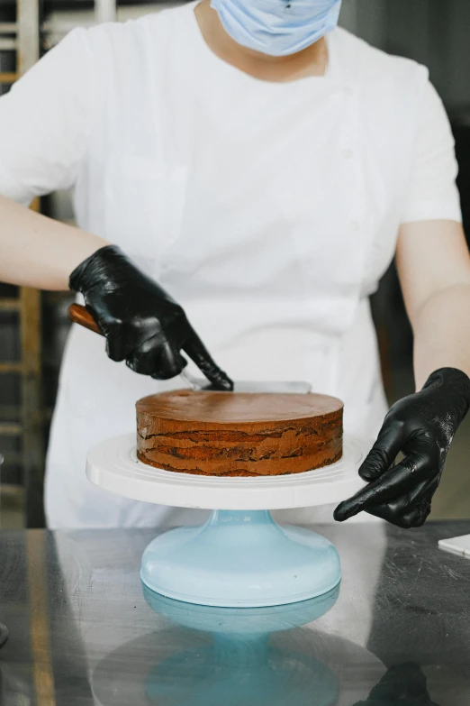 a woman in a face mask cutting a cake, by Julia Pishtar, trending on unsplash, renaissance, wearing gloves, made of smooth black goo, chef hat, chocolate art