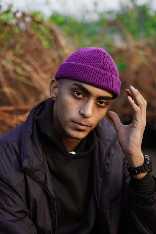 a man in a purple beanie poses for a picture, an album cover, trending on pexels, hasan piker, non binary model, british gang member, arabian