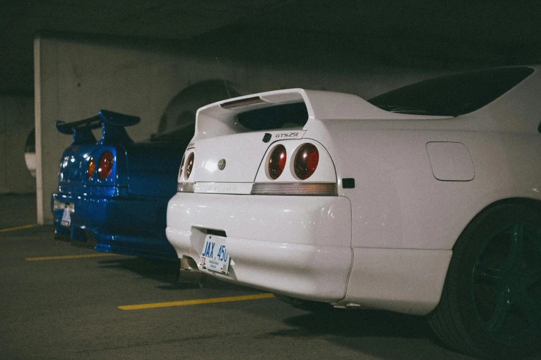 two cars parked next to each other in a parking garage, a photo, unsplash, lyco art, in a modified nissan skyline r34, half rear lighting, white cyc, side view of a gaunt