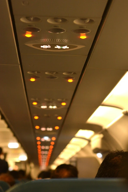 a group of people sitting inside of an airplane, by David Donaldson, flickr, light and space, tactile buttons and lights, suspended ceiling, ambient amber light, in a row