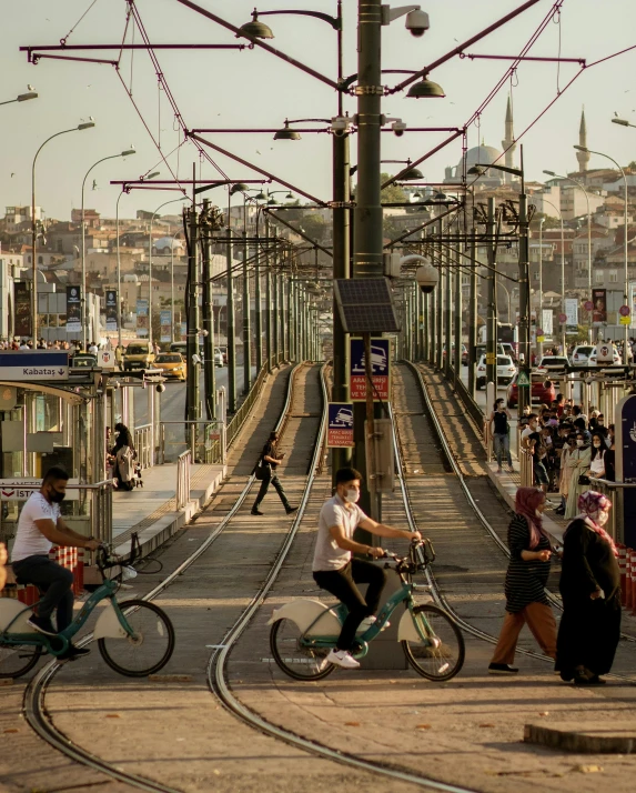 a group of people riding bikes down a street next to a train, pexels contest winner, art nouveau, istanbul, lgbtq, rail tracks, boardwalk