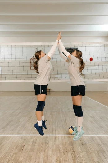 a couple of girls playing a game of volleyball, by Arabella Rankin, unsplash contest winner, arabesque, tall ceilings, holding each other hands, snapchat photo, shiny silver